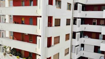 Ein mehrgeschossiges Wohngebäude mit Balkonen, einer flachen Dachterrasse und einem verschlossenen Eingang.
