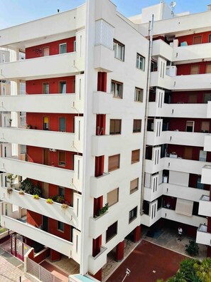 A multi-story residential building with balconies, a flat roof, and a gated entrance. - Apartment by the Sea (Bari)