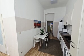 Eine kompakte Küche mit weißen Schränken, einer Waschmaschine und einem Essbereich mit Tisch und Stühlen.
