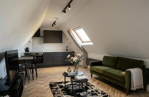A loft-style living space with a dining area, kitchenette, and a green sofa. - Dippen Hall Rural Retreat – Near Gatwick Airport (Lingfield)