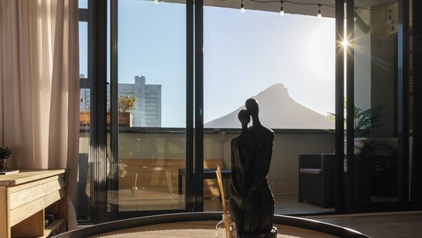 Une pièce moderne avec une grande fenêtre, une table ronde sur laquelle repose un magazine, une statue et une chaise.