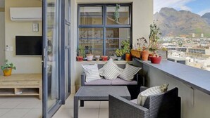 Un balcon avec un canapé, des plantes en pot et une vue sur les montagnes.