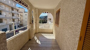 Ein Korridor mit Fliesenboden, einer Deckenleuchte und Blick auf Gebäude durch einen Bogen.