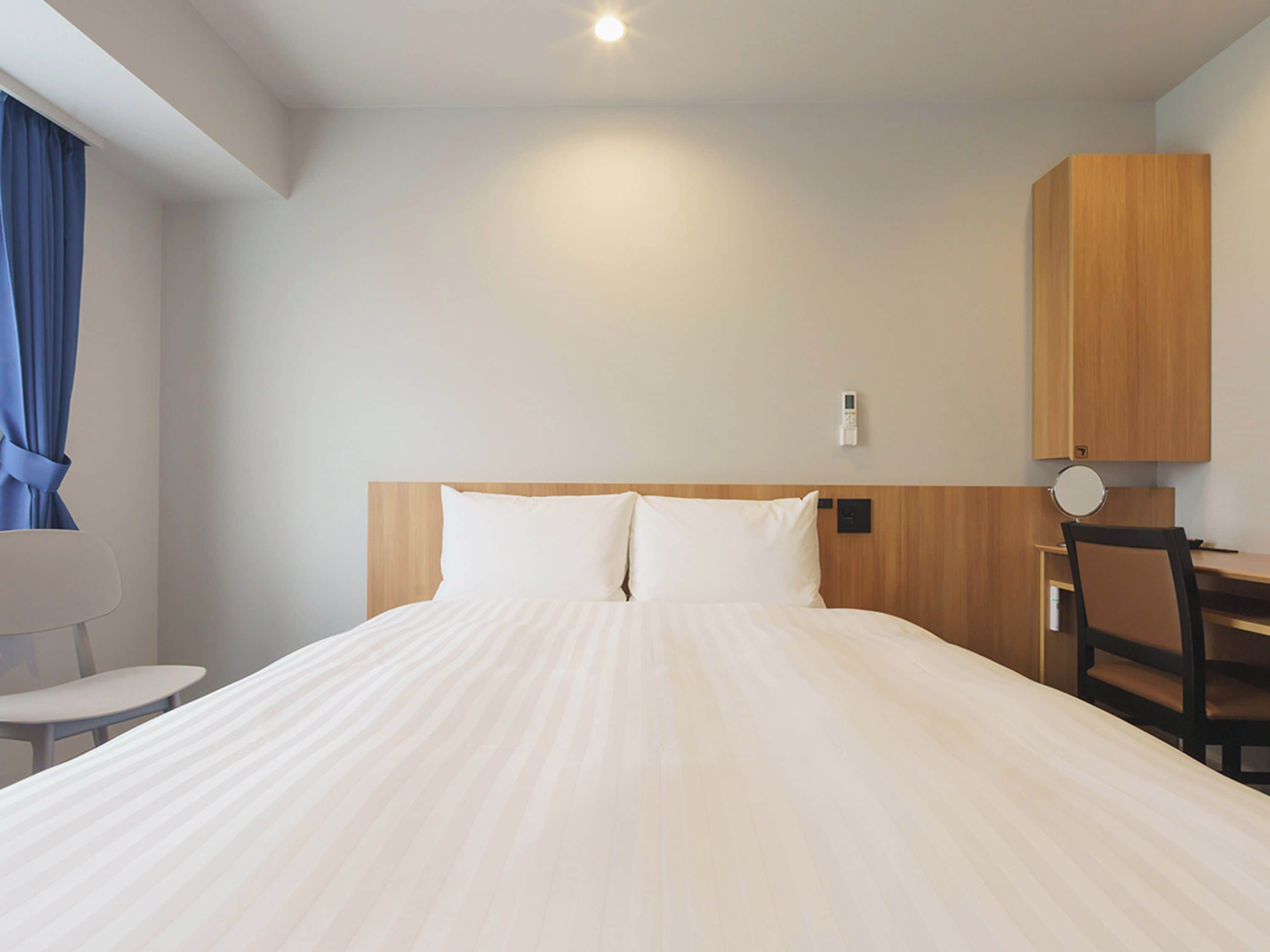 Una habitación de hotel con una cama, un escritorio, una silla y un armario de madera.