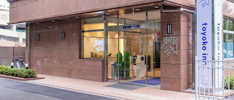 Entrada de hotel con puerta de vidrio, un cartel y una rampa accesible para sillas de ruedas.