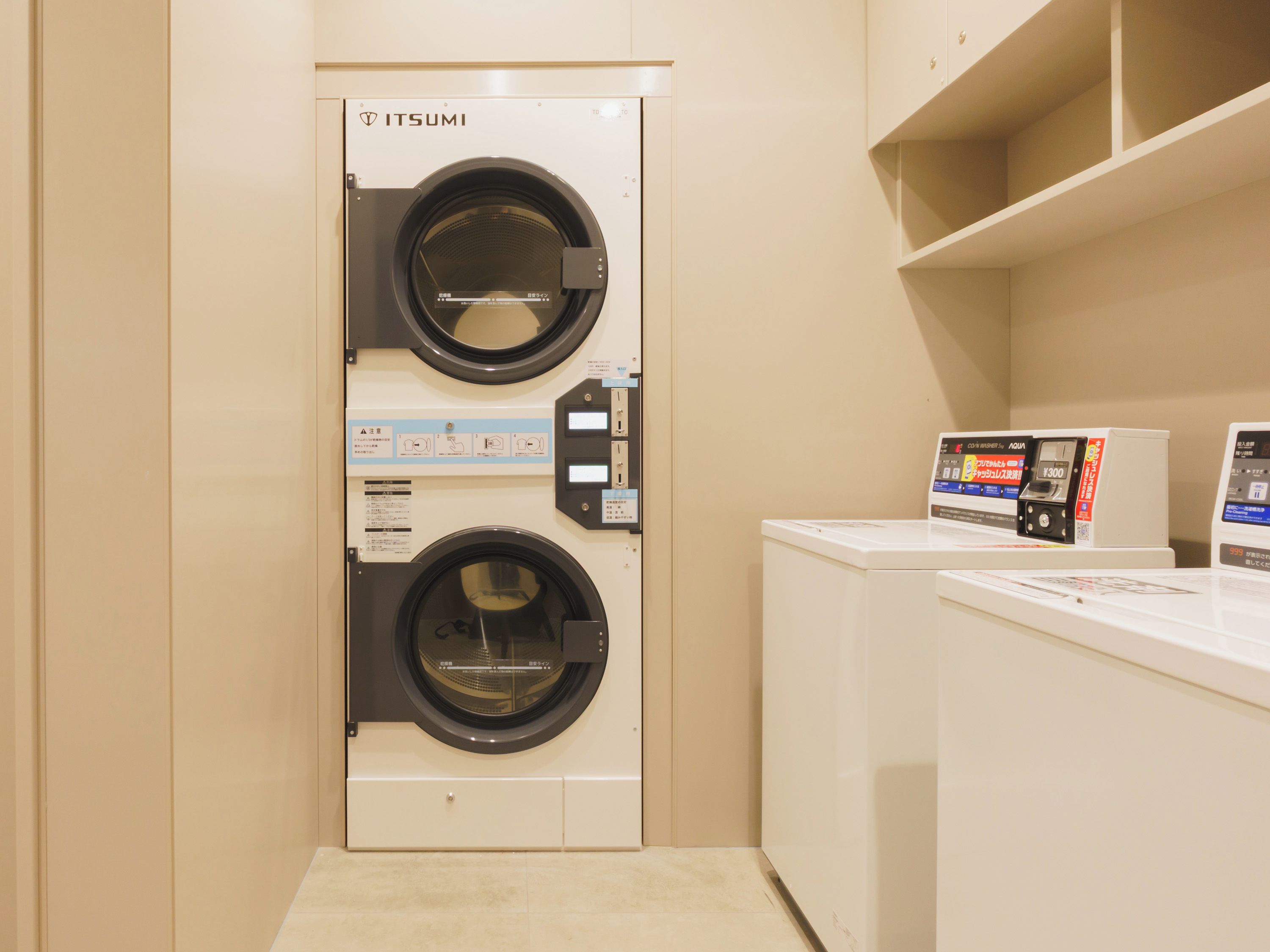 A laundry room with a front-loading washing machine and a dryer, and a control panel with instructions.