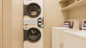 A laundry room with a front-loading washing machine and a dryer, and a control panel with instructions.