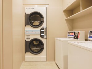 A laundry room with a front-loading washing machine and a dryer, and a control panel with instructions. - Toyoko Inn Tsukuba-eki (Tsukuba)