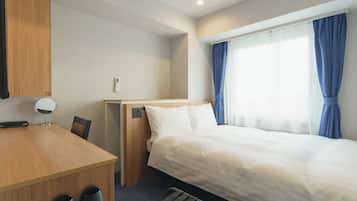 A hotel room with a bed, a desk, a chair, a mirror, and a window with curtains.