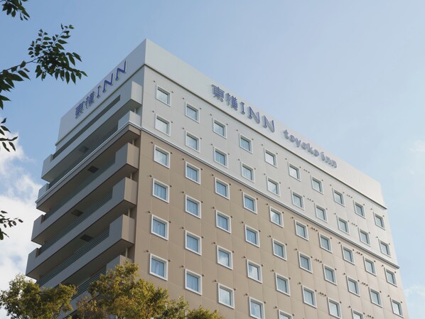 Un edificio de varios pisos con fachada plana, numerosas ventanas y señalización que indica que es un hotel.