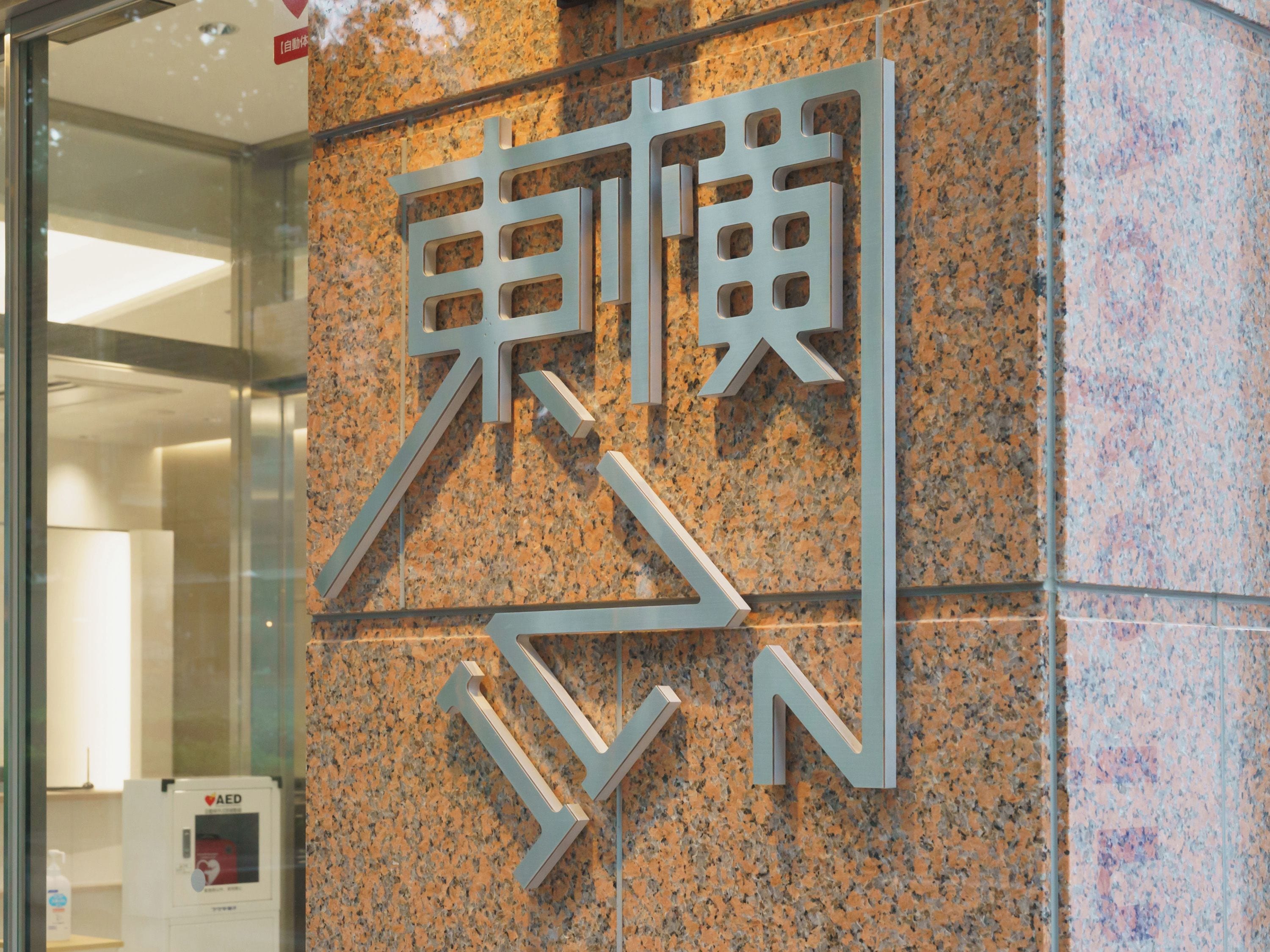 A wall with a large, metallic sign featuring stylized letters.