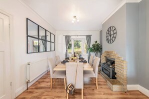 A dining room with a wooden table set for four, a fireplace, and a large mirror on the wall. - Charming 3-Bedroom Wolverhampton Home with Private Hot Tub (West Midlands)
