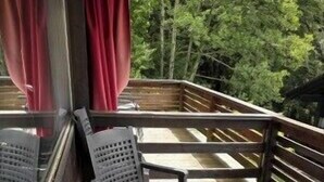 Una terraza de madera con mobiliario exterior, incluyendo mesas y sillas.
