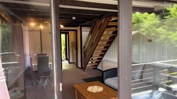 Un interior moderno con una escalera, un separador de vidrio y una zona de estar.