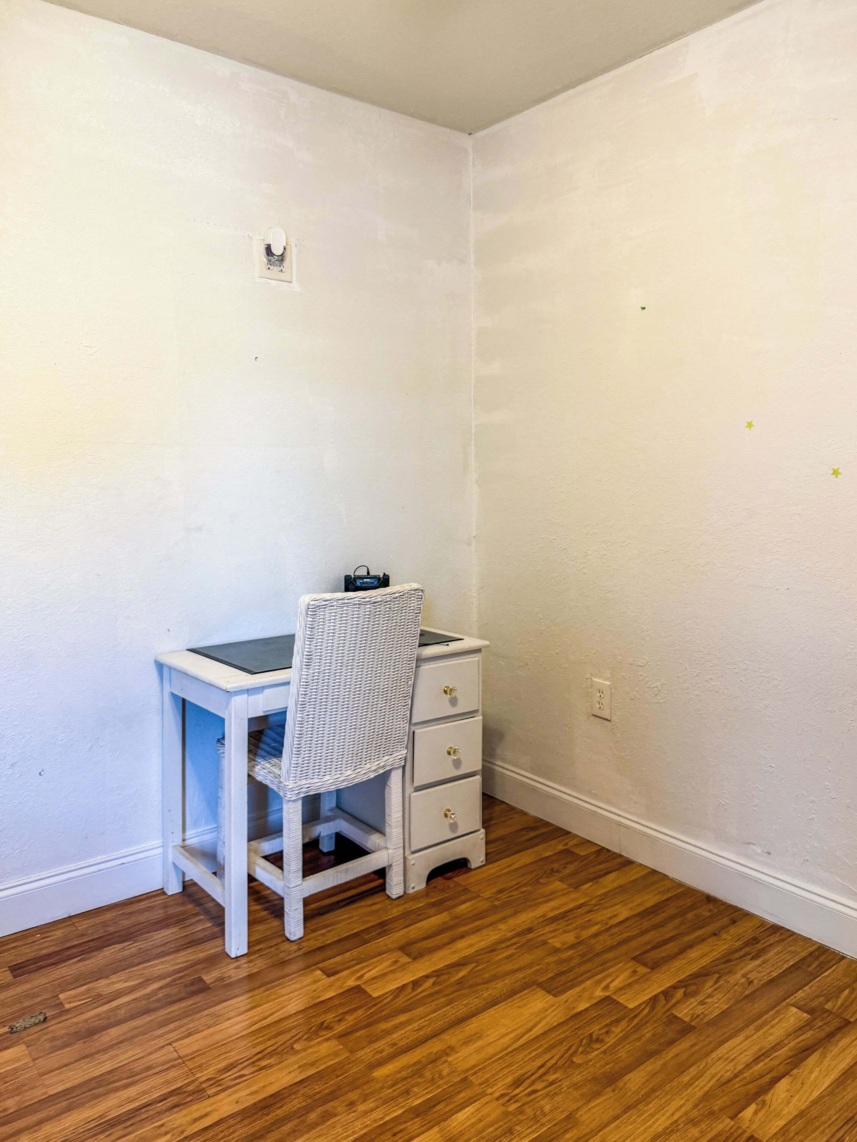 A small room with a desk and chair, a white dresser, and a wooden floor.