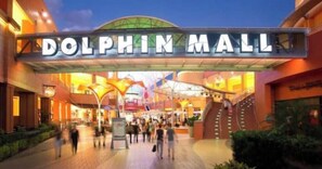 Dolphin Mall with a prominent entrance sign, indoor lighting, and a covered walkway. - Miami Enchanted Studio (Miami Gardens)