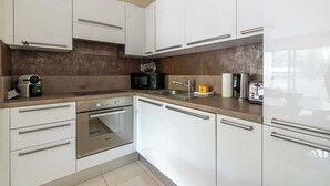 Eine moderne Küche mit weißen Schränken, Edelstahlgeräten und einer braunen Spritzschutzwand.