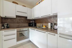 Eine moderne Küche mit weißen Schränken, Edelstahlgeräten und einer braunen Spritzschutzwand.