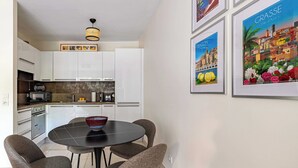 Eine moderne Küche mit weißen Schränken, einem runden Esstisch mit vier Stühlen und gerahmten Bildern an der Wand.