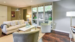 Un salon comprenant un canapé, un fauteuil, une table basse et une lampe. Une porte-fenêtre coulissante donne accès à un espace extérieur.