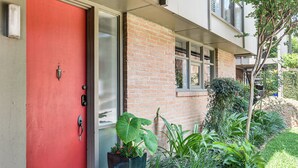 Une porte rouge, un bâtiment en briques et des plantes en pot.