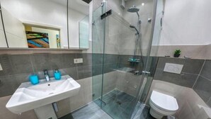 A modern bathroom with a glass-enclosed shower, a white sink, and a toilet. - Ferienwohnung in Orth auf Fehmarn (Fehmarn)