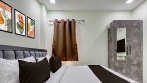 Una habitación de hotel moderna con una cama grande, un cabecero, una zona de ducha con pared de mármol y tres cuadros enmarcados en la pared.