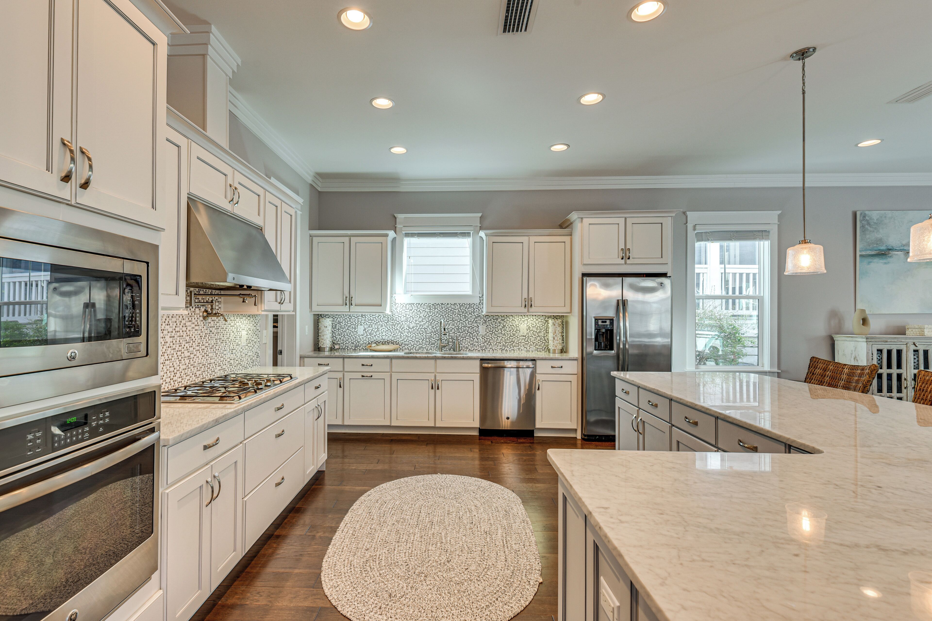 A modern kitchen with white cabinetry, stainless steel appliances, and a large island.