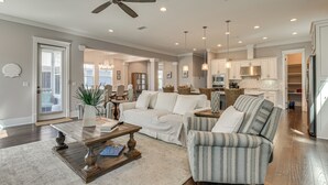 Ein geräumiges Wohnzimmer mit Deckenventilator, Couchtisch, Sofa und einem gestreiften Sessel.
