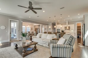 Ein geräumiges Wohnzimmer mit Deckenventilator, Couchtisch, Sofa und einem gestreiften Sessel.