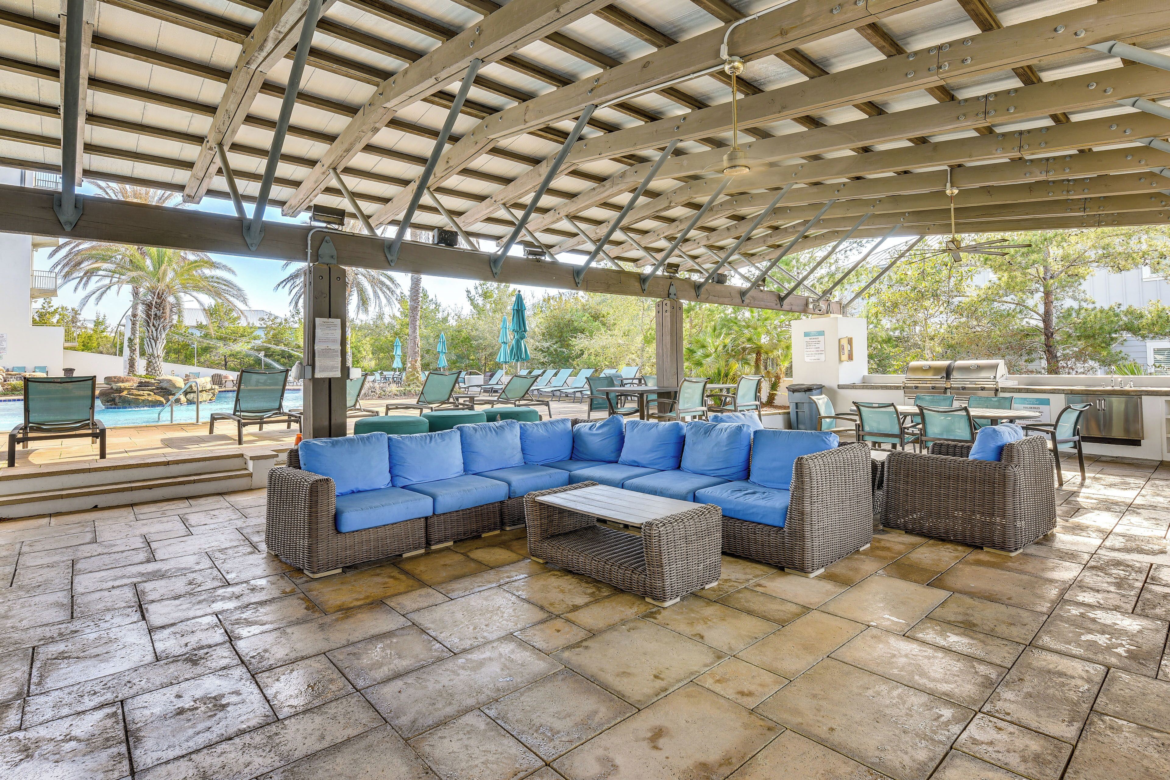 An outdoor patio with a covered seating area, a pool, and a grill.