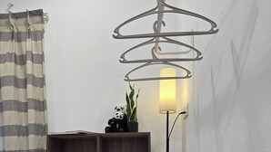 A room with a wooden bookshelf, a small wooden side table with a plant, a hanging light fixture, and a striped curtain. - Tuaran Kampung Villa | Near Dalit Beach & River (Tuaran)