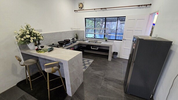 A compact kitchen with a bar stool, a refrigerator, a window, and a door. - Tuaran Kampung Villa | Near Dalit Beach & River (Tuaran)