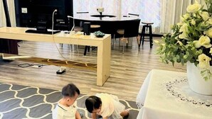 A living room with a TV, a dining table, and two children playing on the floor. - Tuaran Kampung Villa | Near Dalit Beach & River (Tuaran)