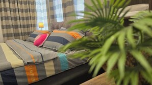 A bed with striped bedding, a potted plant, and curtains. - Tuaran Kampung Villa | Near Dalit Beach & River (Tuaran)