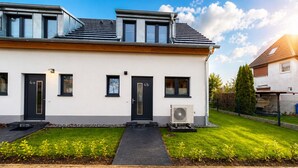 Une maison moderne à deux étages, dotée d’un toit plat, d’une entrée principale et d’un petit jardin à l’avant.
