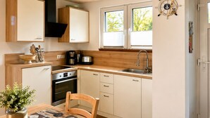 Eine moderne Küche mit Holzausstattung, einem eingebauten Ofen und einem Essbereich mit Tisch und Stühlen.