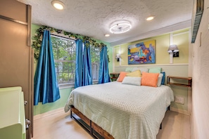 Un dormitorio con cama, cortinas, un cuadro, una lámpara y una ventana.