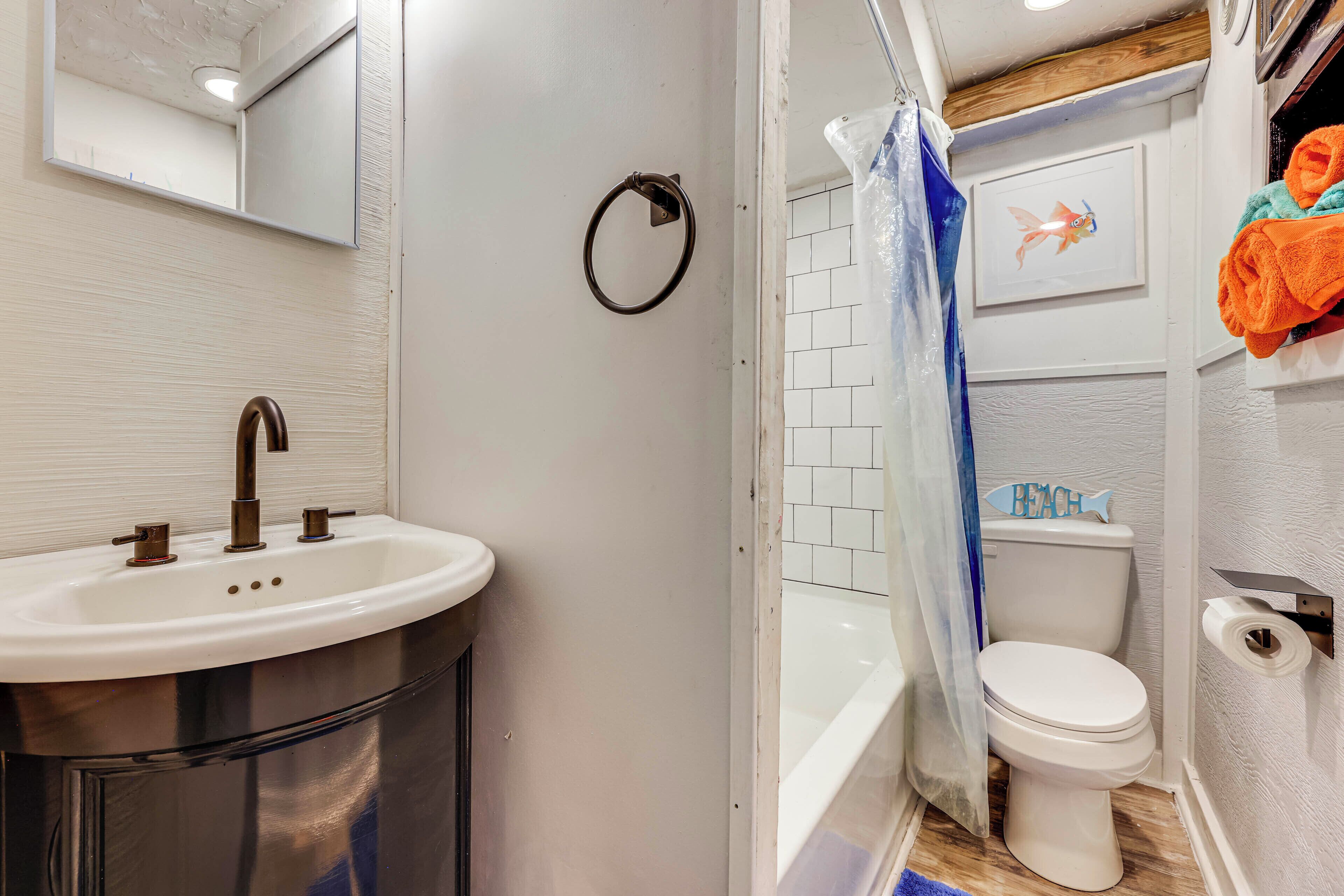 Et badeværelse med håndvask, toilet og bruseforhæng.
