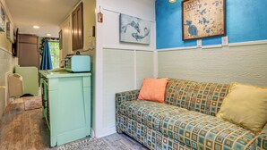 Una cocina compacta con encimera verde, un sofá estampado y un aplique de pared.
