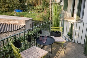 A balcony with two chairs, a small table, and potted plants. - Cozy Countryside Home With Terrace (Brezzo di Bedero)