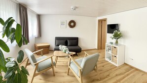 Olohuoneessa on sohva, kaksi nojatuolia, sohvapöytä, televisio ja takka.