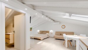 Ein modernes Schlafzimmer im Loftsstil mit Hochbett, Esstisch und einer Couch.