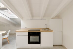 Una cocina compacta con horno integrado, un lavamanos y una encimera de madera.