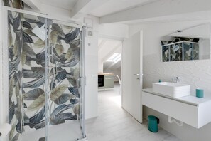 A modern bathroom with a glass shower door, a white sink, and a mirror above it.