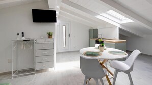 A modern kitchen with a dining area, white cabinetry, a flat-screen TV, and a skylight. - Attic studio, with air conditioning (Castelsardo)