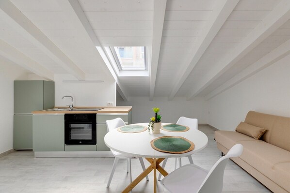 Eine moderne Küche mit Dachfenster, ein Essbereich mit rundem Tisch und eine Sitzecke mit Sofa.