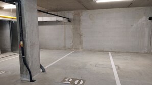 En parkeringskælder med betonvægge, lysstofrør og en parkeringsplads markeret med nummer 20.