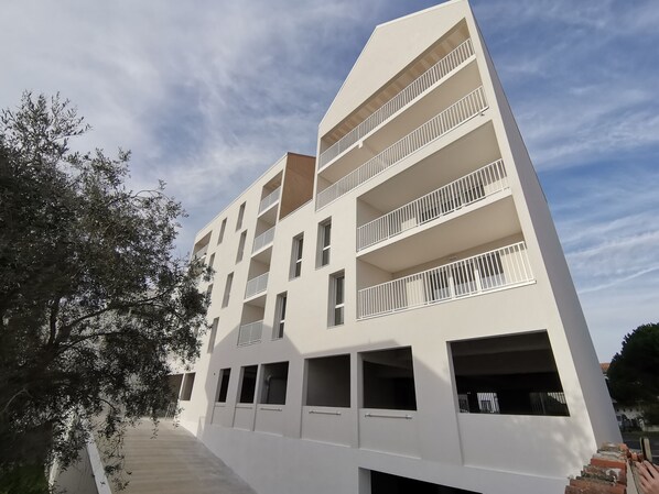 A multi-story building with balconies, large windows, and a clear sky. - Le commandant Lisiack (Aytré)