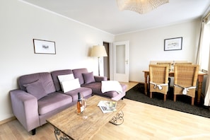 Ein Wohnzimmer mit Sofa, Couchtisch und Essbereich mit Stühlen.